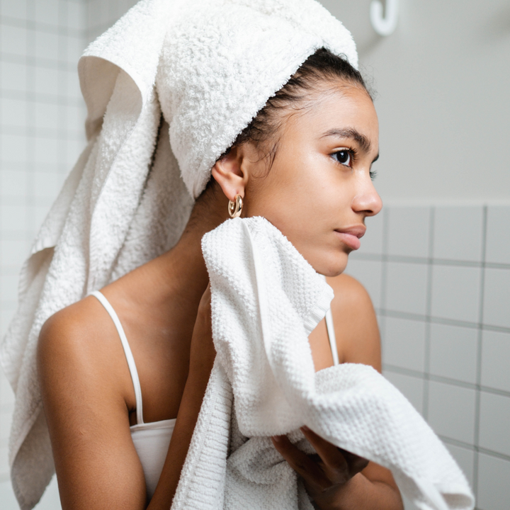 kobieta przed lustrem wyciera twarz ręcznikiem 